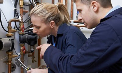 Female Trainee Plumber Working On Central Heating Boiler